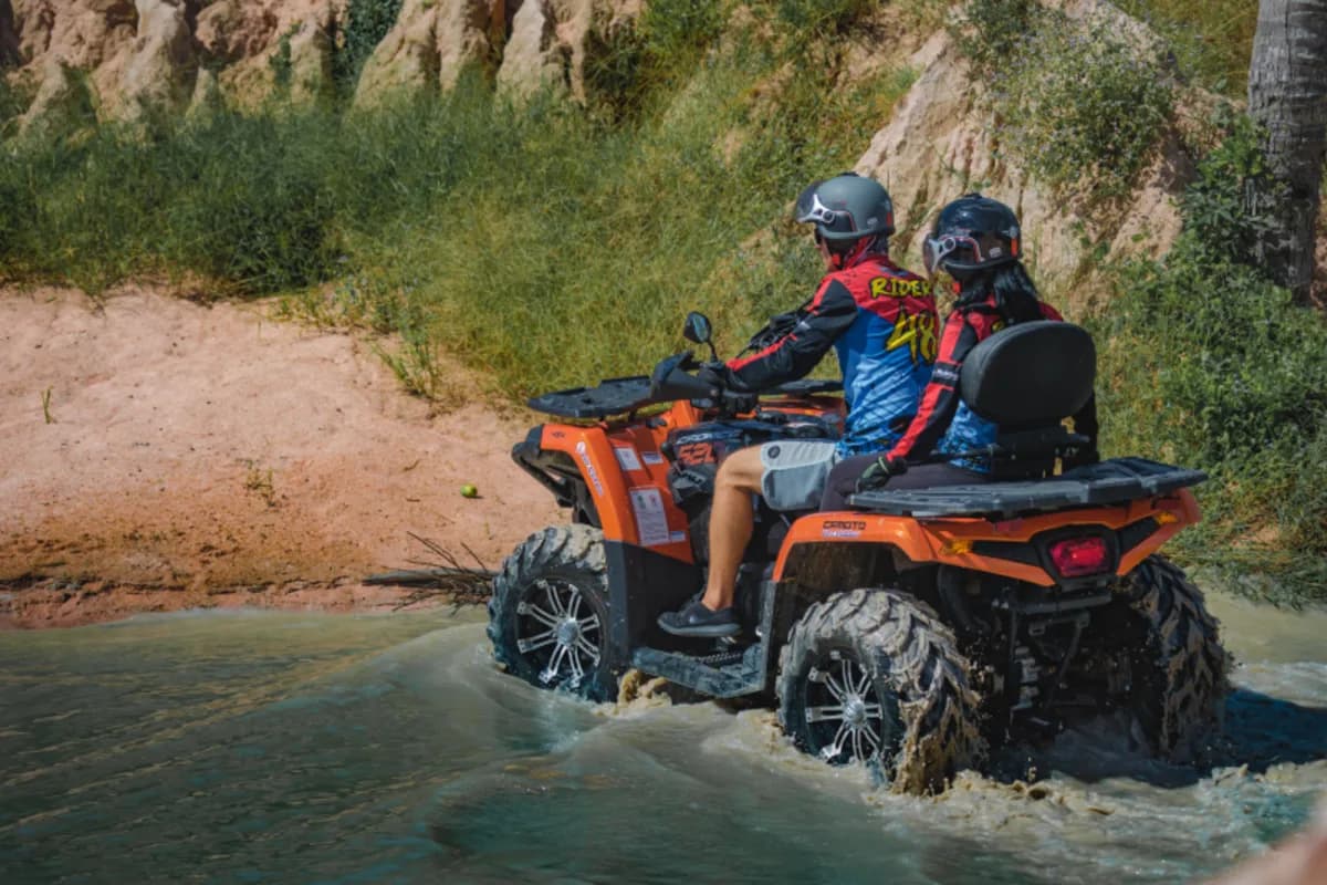 Couple on orange ATV crossing a river on an off-road trail