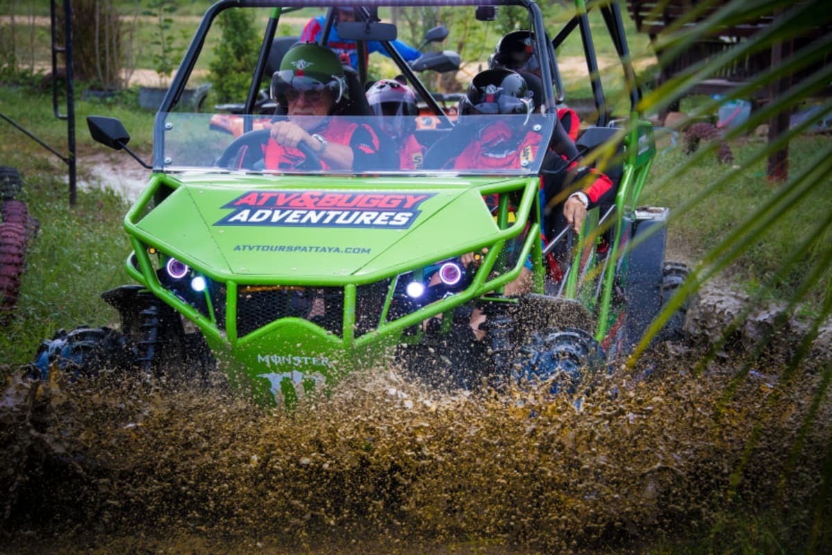 Green buggy splashing through deep mud puddle